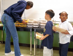 20091207_mongeau_garvin Porshia Garvin helps kindergarteners with their lunch. Though she hasn't cooked this meal for them, she hands it over with a smile.