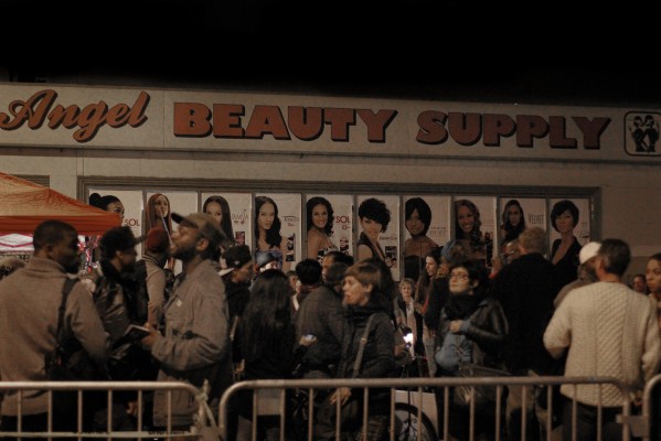 A crowd passes behind a barricade in front of Angel's Beauty Supply store on Telegraph Avenue during Oakland First Friday.
