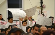 AIMS community members hold posters and flyers to show their support for the schools during a March 20 OUSD meeting.