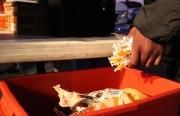 A HEPPAC client drops a handful of used syringes into a medical waste bin at a recent deep East Oakland needle exchange.