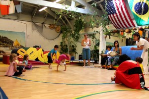 CAPOEIRA_kinder_warriors Marta Frota Bentley (standing, center) and Talita Suassuna (seated, with tambourine) help with the youth capoeira class.