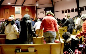 Community members hold hands in prayer, as church leaders advocate violence prevention.