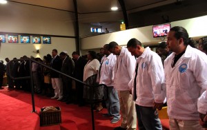 Community members hold hands in prayer.