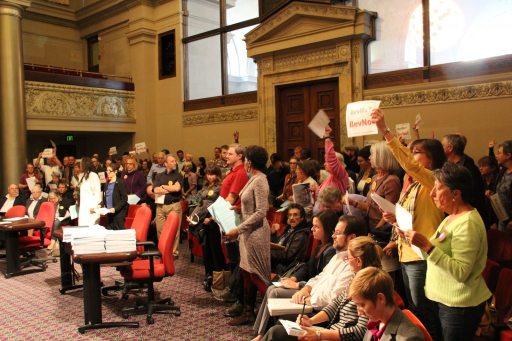 BevMo! repesentatives seated in the front stare straight ahead as residents and business owner from the Piedmont area, opposing the opening of a store on Piedmont Avenue and Montell Street, stand and hold up signs that read BevMo!? BevNo! during the city planning and commission meeting Wednesday.