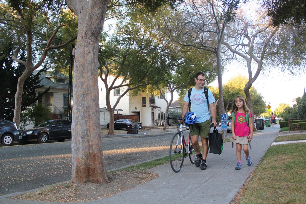 Raphael Breines, Safe Routes to School site coordinator for Peralta Elementary, walks with his daughter on Wednesday.
