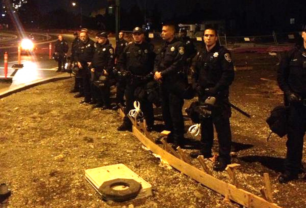 A police line at 12th Street and Lake Merritt watch protesters move by. Photo by Sam Rolens.