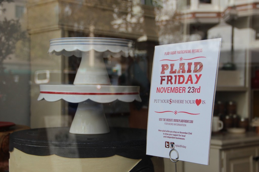 Plaid Friday placard displayed in the window of Marion and Rose's Workshop in Old Oakland. The shop's owner, Kerri Johnson, started Plaid Friday in 2009.