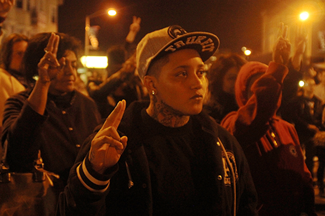 Oakland resident, Jazzmine Lesure holds a peace during the moment for silence Kiante Campbell, who was shot and killed during last month's event