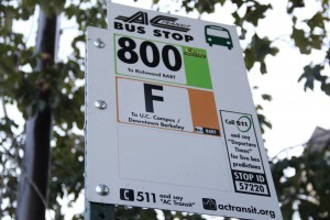 A closeup for a bus stop sign the shows two bus routes, the 800 and the F. The numbers and letter are in bold black against a white rectangular sign.