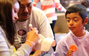 A boy makes a Halloween mask with his parents.