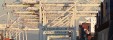 A terminal at the Port of Oakland shows a series of elevated horizontal white steel bars with the words "Port of Oakland" over frames that say "Terminals ZPMC"