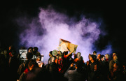 Ronald Cruz, center, an organizer with By Any Means Necessary (BAMN), directs protesters back to downtown Oakland from the 580 freeway as smoke from a burning mattress billows behind him. November 24, 2014. (Photo by Bonnie Chan)