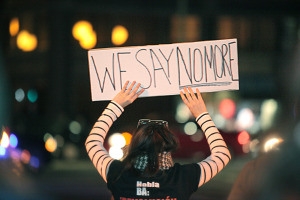 Nova Tiller holds a sign during a protest in downtown Oakland early in the evening. Photo by Deana Mitchell.