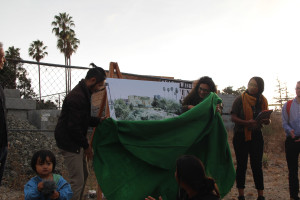 Cliff Lau and Dunya Alwan remove the green felt cover and unveil the plans.