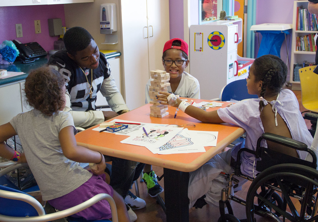 Amari Cooper joins in a game of Jenga with seven-year-old Melania Bevu (far right) and her siblings, Ruth (left) and Jim.