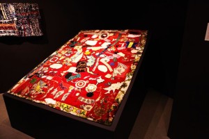 Foreground: "Unfinished (red velvet and Embroidery)". Pieced by Rosie Lee Tompkins. Background: "Wall Piece" Pieced by Rosie Lee Tompkins, Quilted by Irene Bankhead.