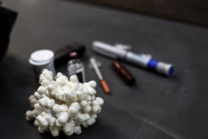 A 3D printed model of the insulin molecule sits next to a vial of insulin and a syringe.