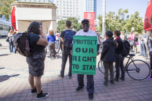 Causa Justa member, lifelong Oakland resident Zane Burton holds a homemade sign to protest unfair rent increases.