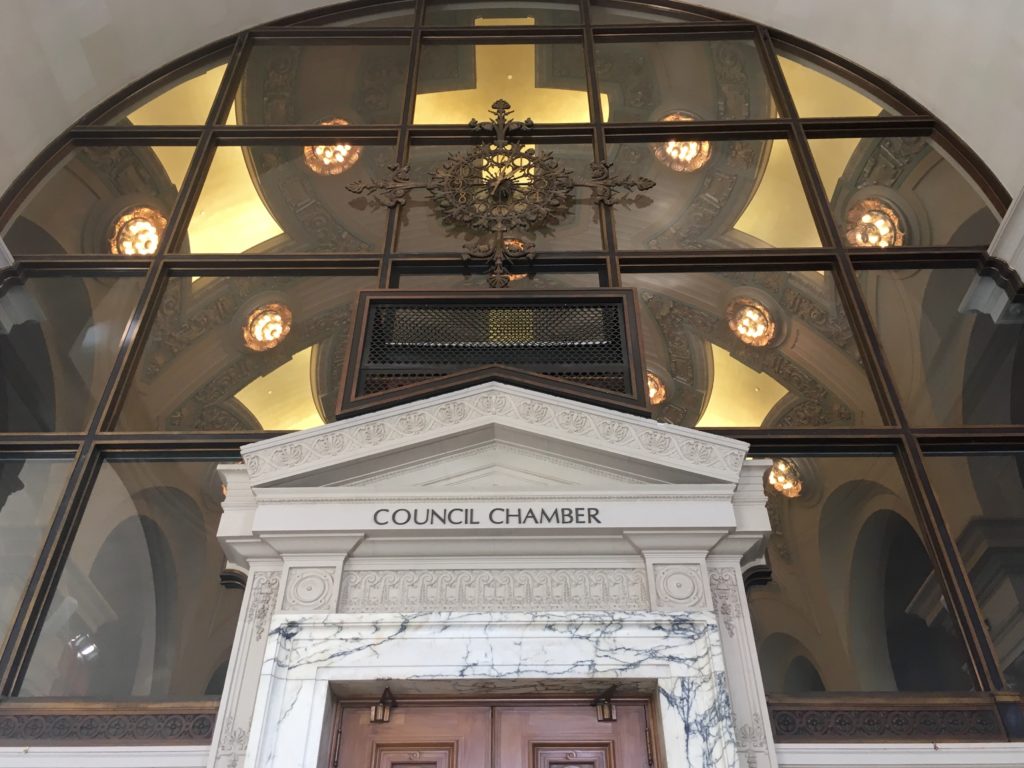 Above two wooden doors is a white gable under which are the words "council chambers"