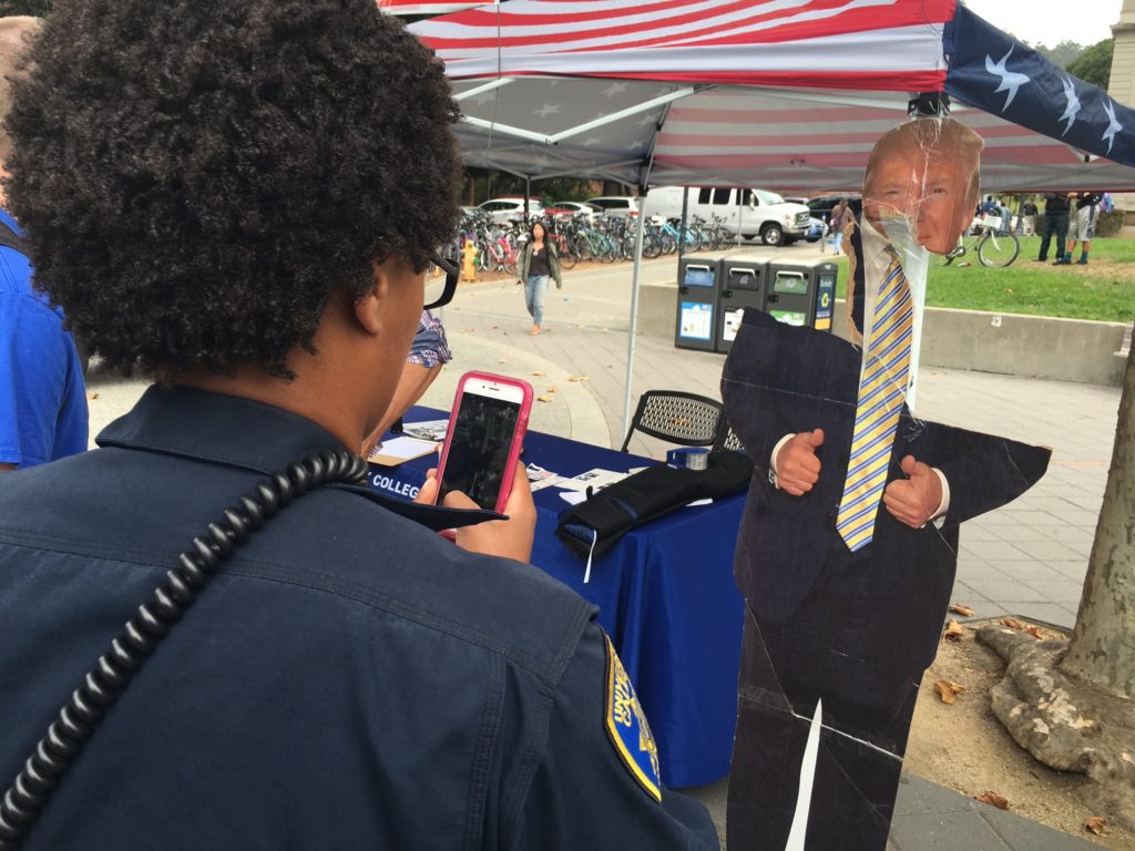 At the Berkeley College Republican recruiting table at the Sather Gate on the UC Berkeley campus Donald Trump's cut-out poster was damaged after a group of protesters ripped it. Here, a campus police officer is taking a photo for her report. Photo by Khaled Sayed