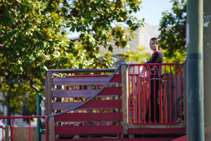A woman watches over her children playing in the swings at Lincoln Square Park on Thursday October 13, 2016. (Yesica Prado/Oakland North)