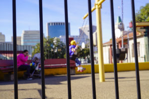 A boy plays in the swings while his mother watches him from a nearby chair at Lincoln Square Park on Thursday October 13, 2016. (Yesica Prado/Oakland North)