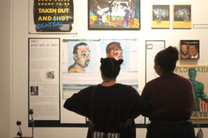 Spectators look on at Brett Cook’s “Protect and Serve,” part of Betti Ono’s current exhibit, “Viral: 25 Years after Rodney King.” Photo by Briana Flin.