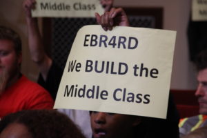 A member of the East Bay Residents for Responsible Development group holds a sign during the public comment section of Tuesday's meeting.