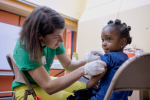 Kate Holbrook prepares Nkem Nezemekelsih, a pupil at Cleveland Elementary School, for her flu shot as part of Shoo the Flu's vaccination campaign. Photo by Rosa Furneaux.
