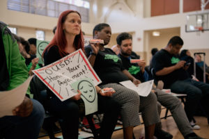 Oakland Education Association (OEA) member Dorota Hryniszak holds a Payday candy bar and protest signs at this week's school board meeting. The OEA protested a proposal to reduce a salary increase for OUSD faculty and staff. Photo by Rosa Furneaux.