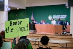 A protest sign is held by an Oakland Education Association member at this week's school board meeting. Photo by Rosa Furneaux.
