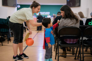 Emiliano Arroyo, helped by his mother Becca Rozo (left), hands out Payday candy as part of an Oakland Education Association protest at this week's school board meeting. Photo by Rosa Furneaux.