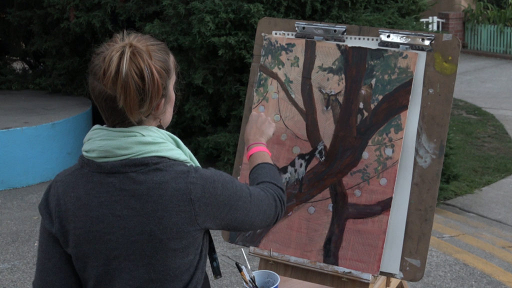 An artist painting a picture that will be auction off later in the night.