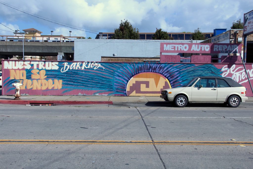 A mural painted on a fence close to Fruitvale Station reads “Nuestros barrios no se venden.” You can't sell our neighborhoods, in English. Photo by Laura Newberry
