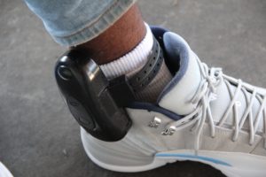 Kamani Holmes shows his GPS ankle monitor. Photo by Rachel Loyd.
