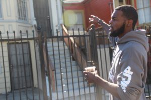 Kamani Holmes points to the house where his grandmother used to live and police would raid on late nights. Photo by Rachel Loyd.