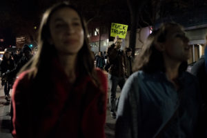 A protester carriers a sign reading "Fuck Trump." Photo by Rosa Furneaux.