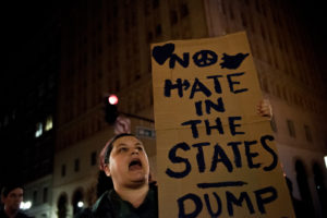 As the march pauses at an intersection downtown, a protester carries a sign reading "No hate in the States." Photo by Rosa Furneaux.