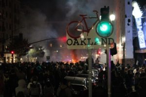 Crowds throng around burning refuse bins. Photo by Jacob Shea.