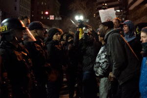 Towards the end of the night, protesters' anger was directed at the Oakland Police Department. Here, a man shouts at officers as they prevent marchers from walking again on Broadway. Photo by Rosa Furneaux.