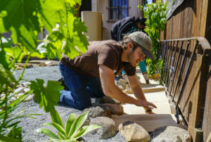 Trevor Probert, StopWaste contractor, lays cardboard as the first layer of the process of sheet mulching at the Memorial Tabernacle Church for a lawn party to restore the church's garden on Saturday, May 6, 2017. (Yesica Prado/Oakland North)