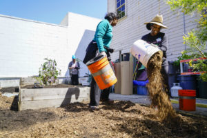Volunteers lay the third layer of sheet mulching, wood mulch, at the Memorial Tabernacle Church for a lawn party to restore the church's garden on Saturday, May 6, 2017. (Yesica Prado/Oakland North)
