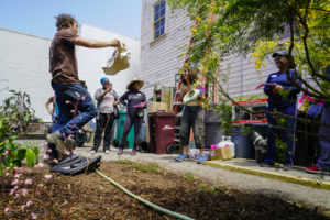 Volunteers laugh and smile as Trevor Probert raffles a StopWaste bag at the Memorial Tabernacle Church for a lawn party to restore the church's garden on Saturday, May 6, 2017. (Yesica Prado/Oakland North)