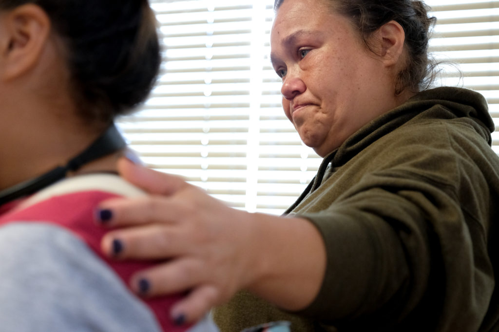 Teddie Moorehead, 40, places her hand on her daughter Che-Kwis Hernandez, 12, who spoke to a room full of East Oakland residents about her experiences as a witness to sex trafficking in her neighborhood. Photo by Lisa Hornak