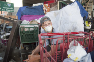Corvin Busche, a student at Leipzig University of Applied Sciences in Germany studying Oakland's homeless community, sits in front of a homeless encampment in Oakland. He said that he could see a thin layer of white ash from the smoke caused by the wildfires. “It was like making a fire in the woods,” he said.