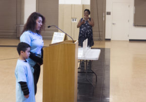 A mother and her son speak during the public comment period at the OUSD board meeting. The two were as part of a group representing the California Charter School Association. Photo by Hyowon Lihinag-Tam.