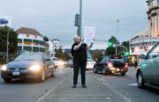 Mary Loeser, a 4th grade teacher at Cleveland Elementary, holds up a sign between lanes of traffic during a demonstration in response to possible OUSD budget cuts. Photo by Anne Wernikoff