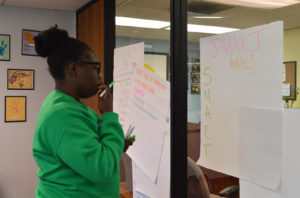 Ashlee T. Jemmott, PEERS program coordinator, starts the planning of a poster where the group listed their goals as TAY leaders.