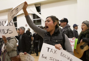 Child development teacher Natalia Hernandez carries signs and chants 'no cuts to kids,' during a protest against budget cuts at the OUSD school board meeting on Monday evening at La Escuelita. Photo by Anne Wernikoff