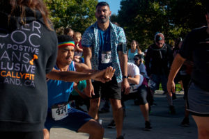 Run participant Matt Randoph stretches to Page's instructions in preparation for takeoff. Following the run, Randoph said, "I really appreciated how much the 5K was about building community, and the reference to ancestors in the beginning [made by Oakland LGBTQ Center's Kin Folkz/Monica Anderson]." He added, "It really fueled me."
